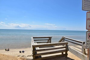Una banchina di legno che conduce a una spiaggia sabbiosa, con vista libera sull'oceano.