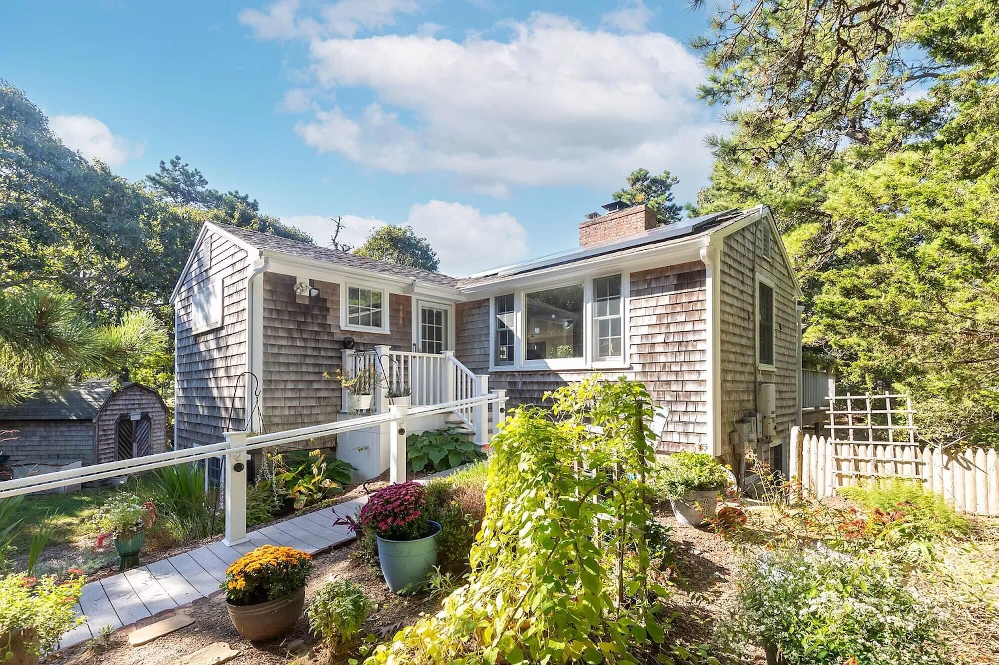 Une maison avec un porche couvert, un petit jardin et une clôture en bois.