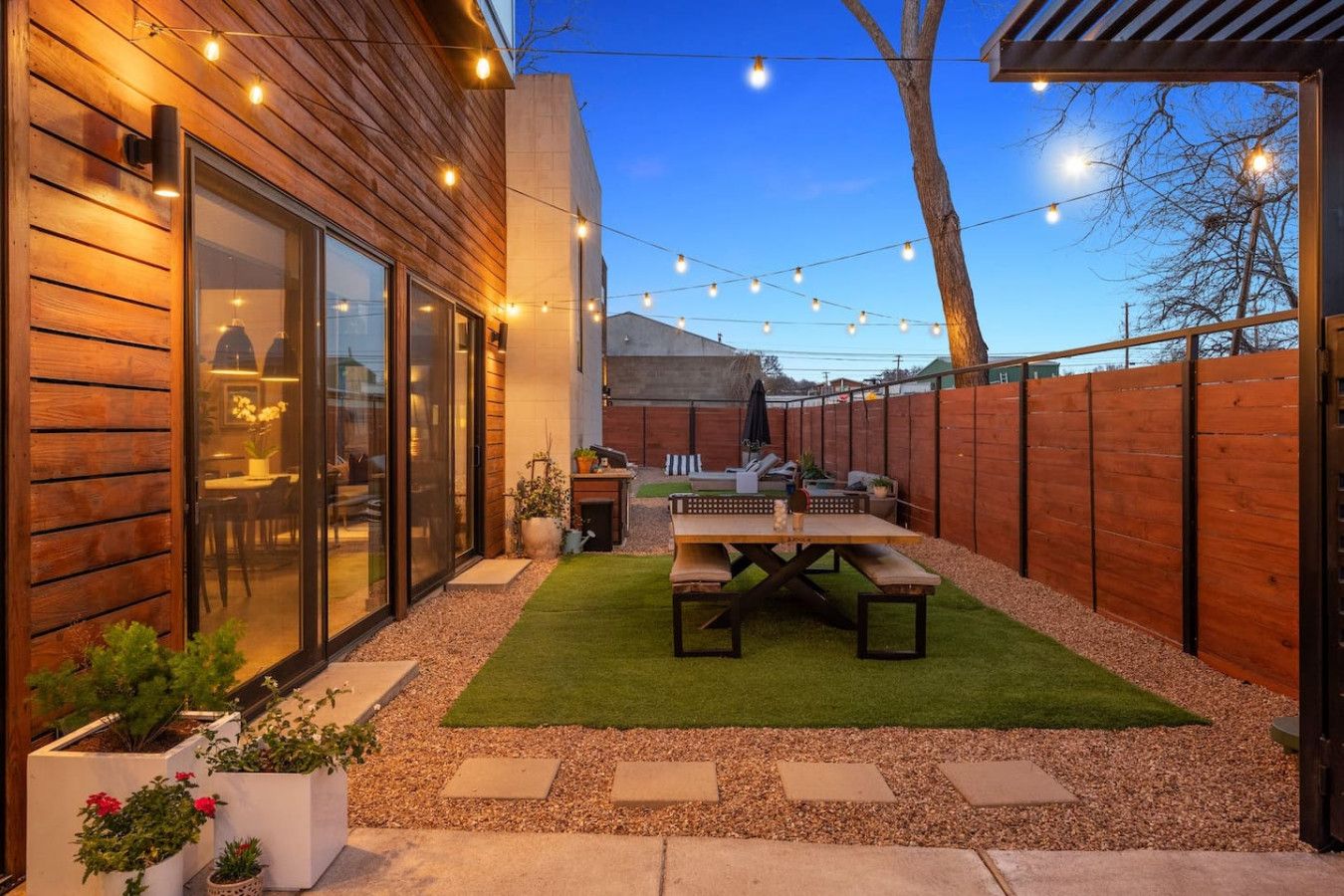 A backyard with a wooden deck, a barbecue area, and a patio with a table and chairs.