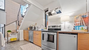 A modern kitchen with a built-in oven, a refrigerator, and a microwave. There is a staircase leading to an upper level. - NEW Luxe DT Austin Oasis | Pool | Casita (Austin)