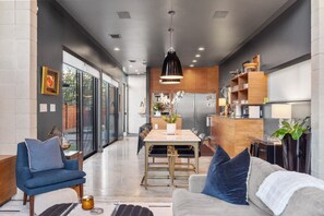 Une cuisine moderne avec des meubles en bois, un coin repas avec une table et des chaises, et un salon avec un canapé et des fauteuils.