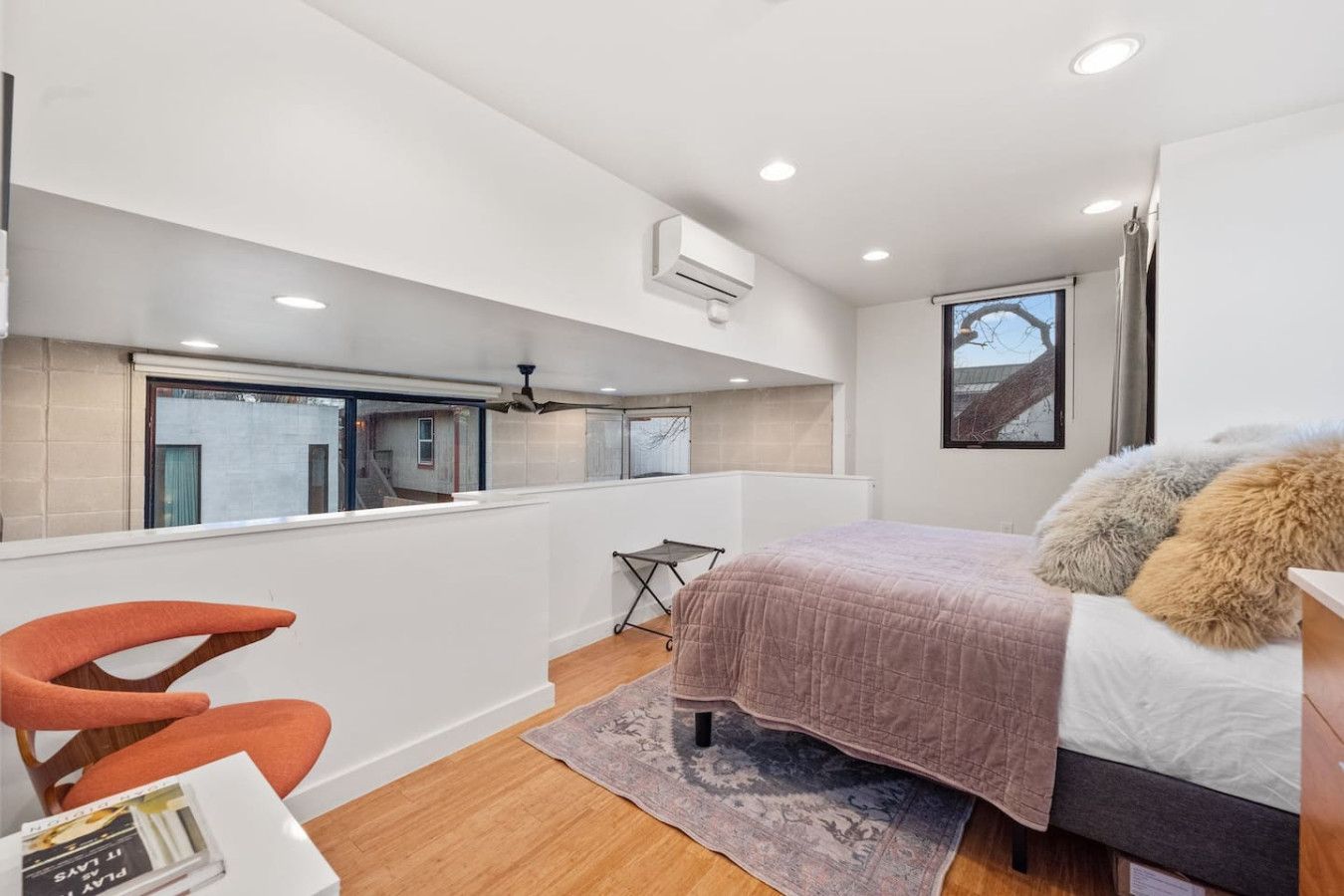 A modern bedroom with a bed, a desk, and a window overlooking a balcony.