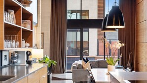 A modern kitchen with wooden cabinets, a coffee machine, and a dining area with a sofa and table. - NEW Luxe DT Austin Oasis | Pool | Casita (Austin)