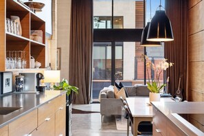 Una cucina moderna con mobili in legno, una macchina per il caffè e un'area pranzo con divano e tavolo.
