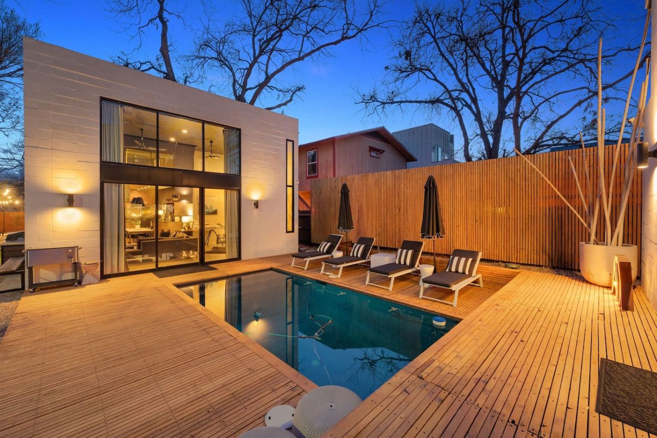 Uma casa moderna com piscina, deck de madeira e espreguiçadeiras.
