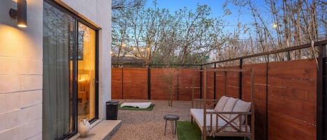 Eine moderne Außenpatio mit Holzzaun, einer Sitzecke mit Kissen und einem kleinen Tisch.