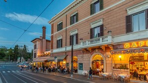 A historic building with a cafe on the ground floor, featuring outdoor seating and a classic architectural style. - Iconic apartment with unique Colosseum view (Roma)