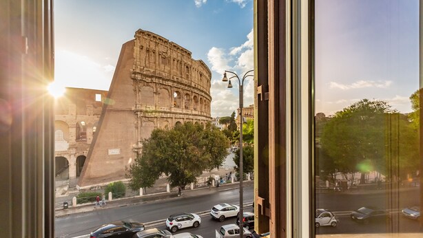 A view of the Colosseum from a window overlooking a street with cars and pedestrians. - Iconic apartment with unique Colosseum view (Roma)