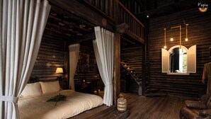 A log cabin-style bedroom with a bed, curtains, a chair, and a hanging light fixture. - P'apiu Resort (Ngoc Duong)