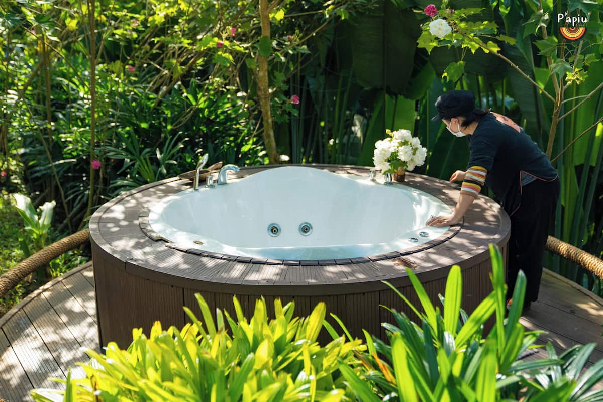 A hot tub surrounded by lush greenery and a wooden deck.