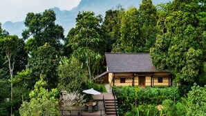 A house with a balcony overlooking a lush garden and a mountainous backdrop. - P'apiu Resort (Ngoc Duong)