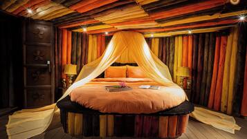A circular bed with a canopy, wooden walls, and a wooden floor.