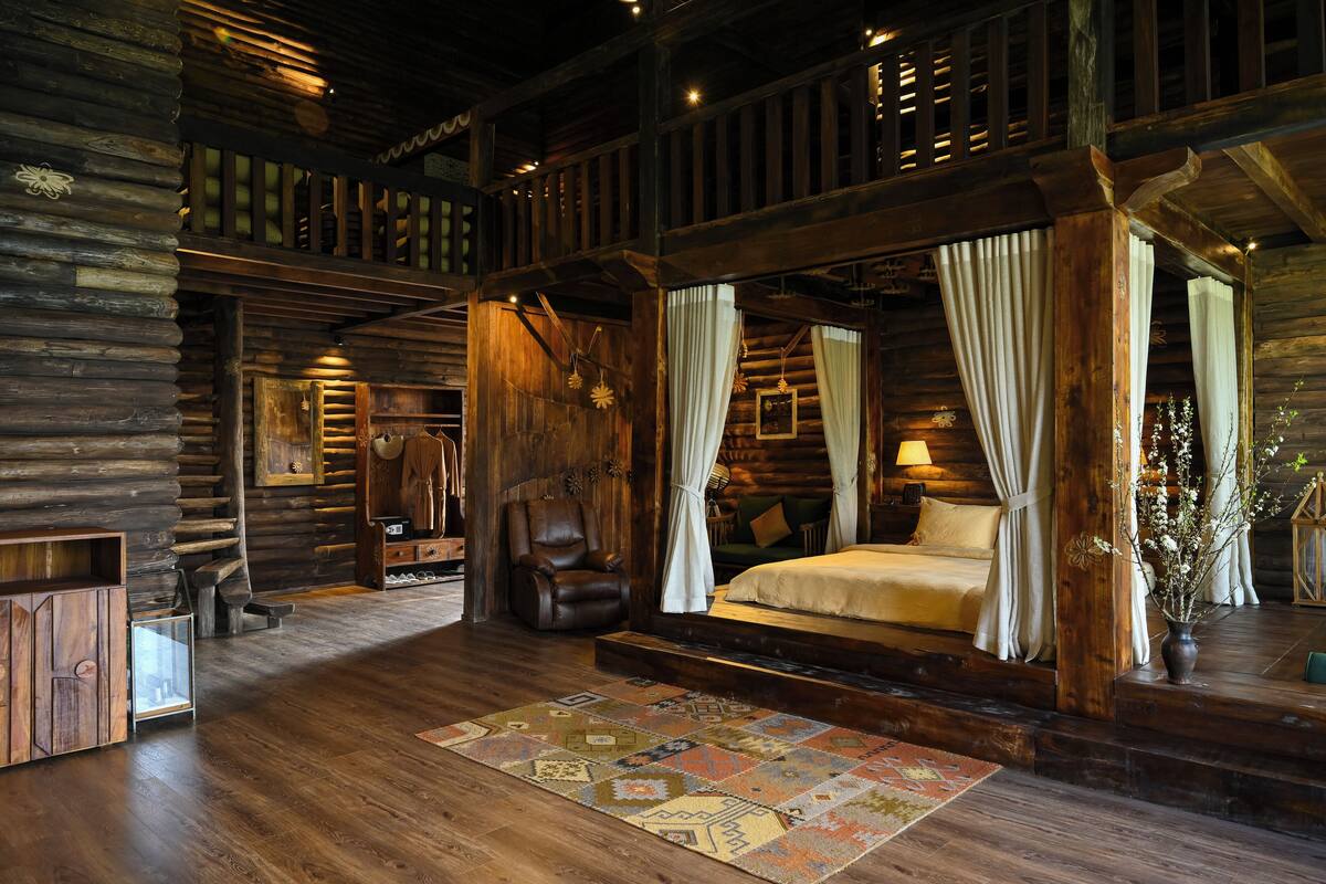 A log cabin-style bedroom with a large bed, wooden walls, and a rustic decor.