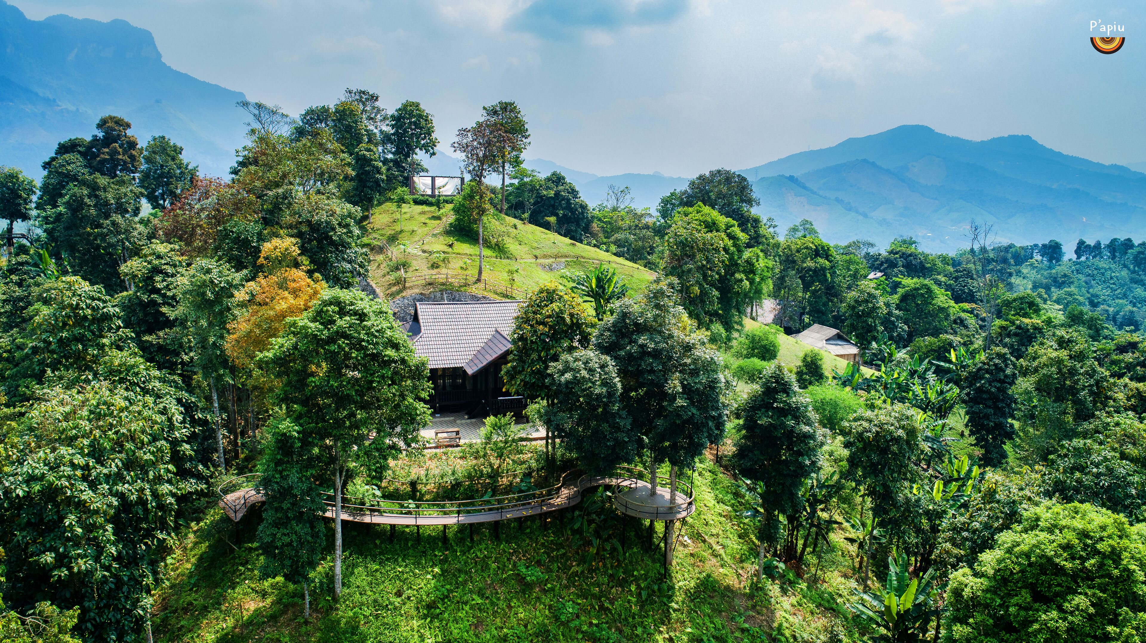 A traditional wooden house surrounded by lush greenery and hills.