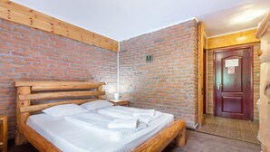 A wooden bed with white linens in a room with brick walls and a wooden door. - RESORT 7 CRAI (Zarnesti)