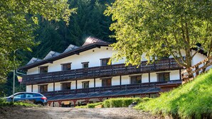 A traditional chalet with a wooden balcony, a dirt path leading to the entrance, and a forested hillside in the background. - RESORT 7 CRAI (Zarnesti)