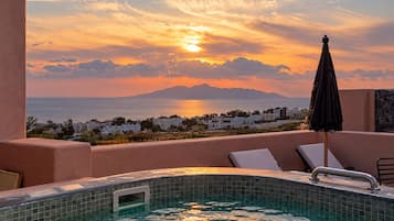 Ein Pool mit Blick auf das Meer und einen Sonnenuntergang.