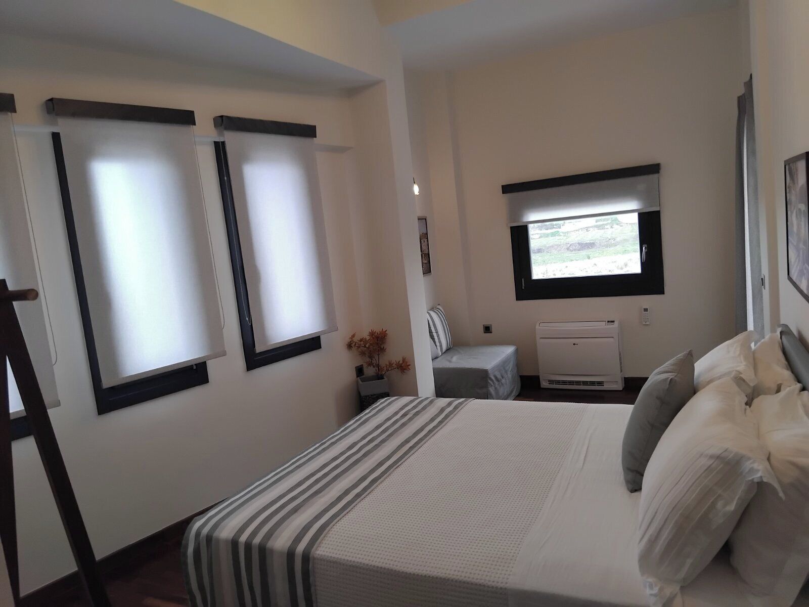 Una camera da letto con un letto, un comodino, una finestra e un condizionatore.
