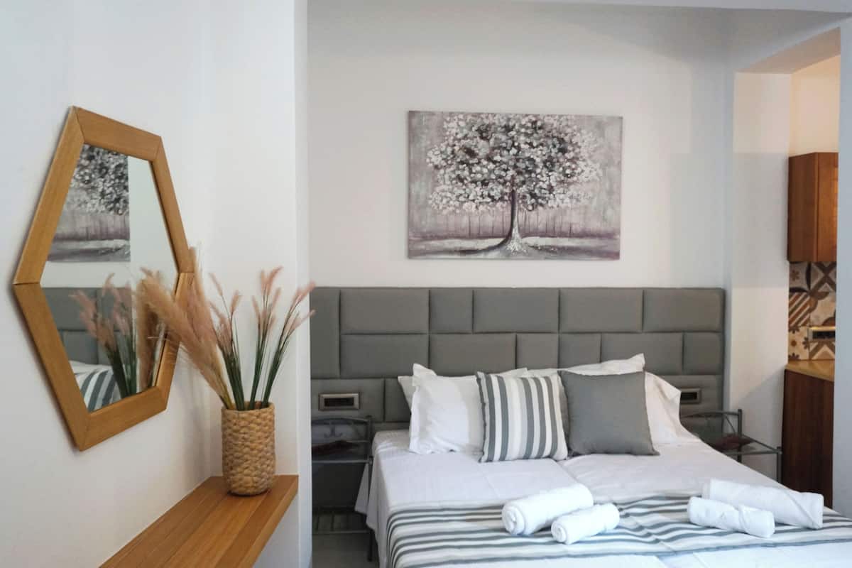 Quarto bem arrumado com cama, mesas de cabeceira, espelho e obras de arte na parede.