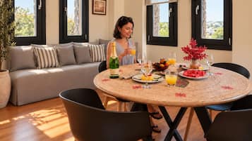 A dining area with a round table, chairs, a sofa, and a potted plant.
