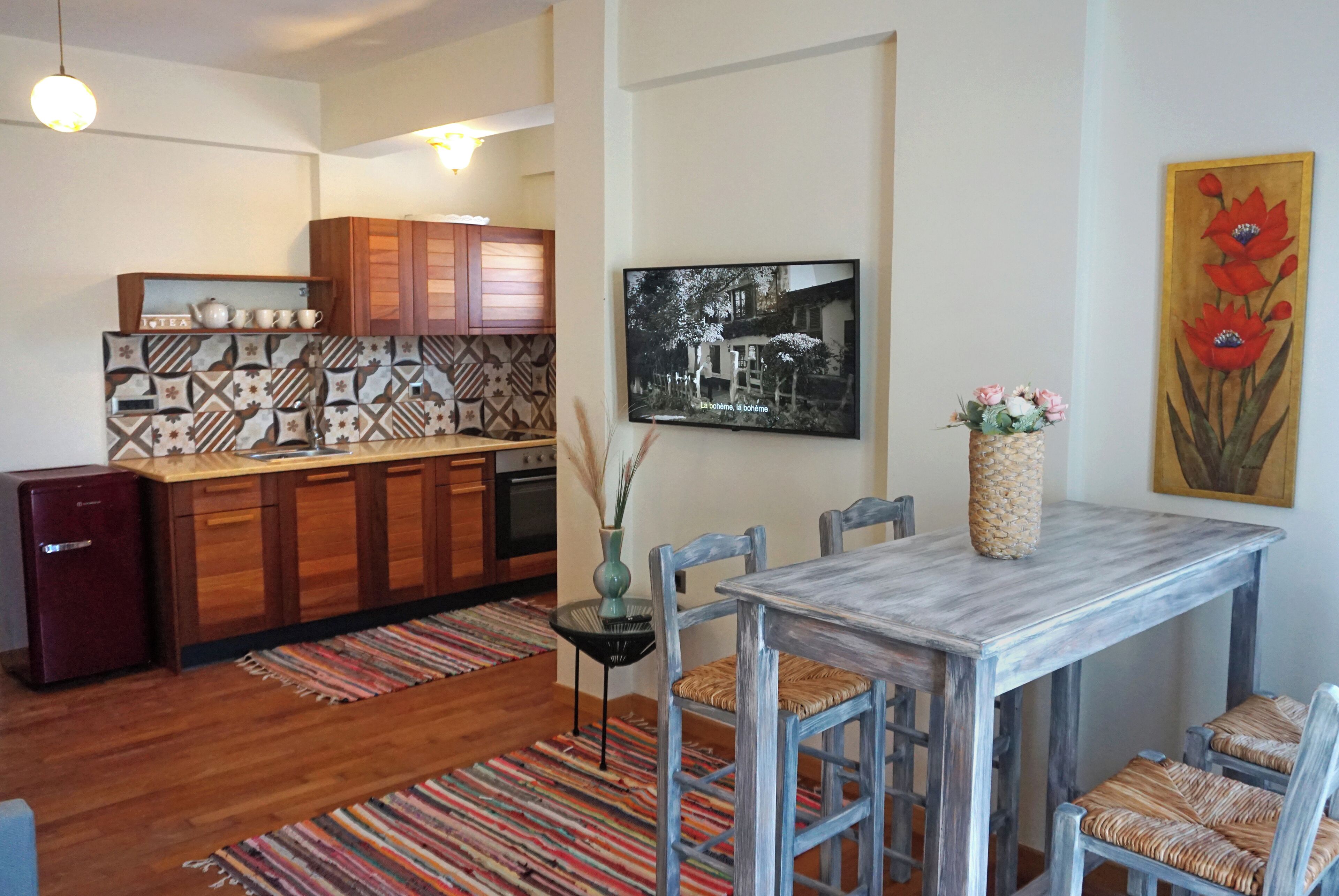 Een moderne keuken met houten kastjes, een eettafel met stoelen en een kleurrijk tapijt.