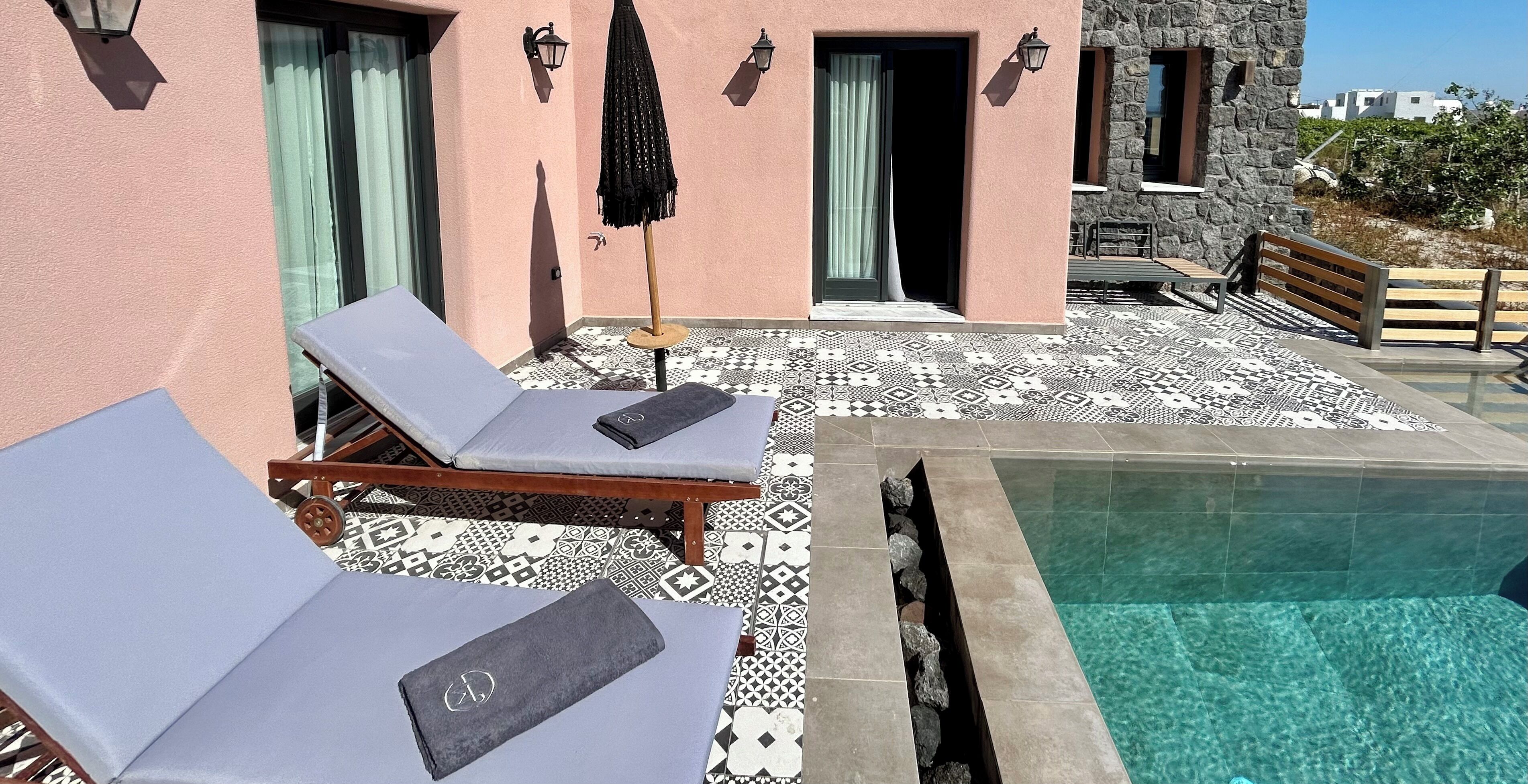 A pool area with lounge chairs and a stone building in the background.