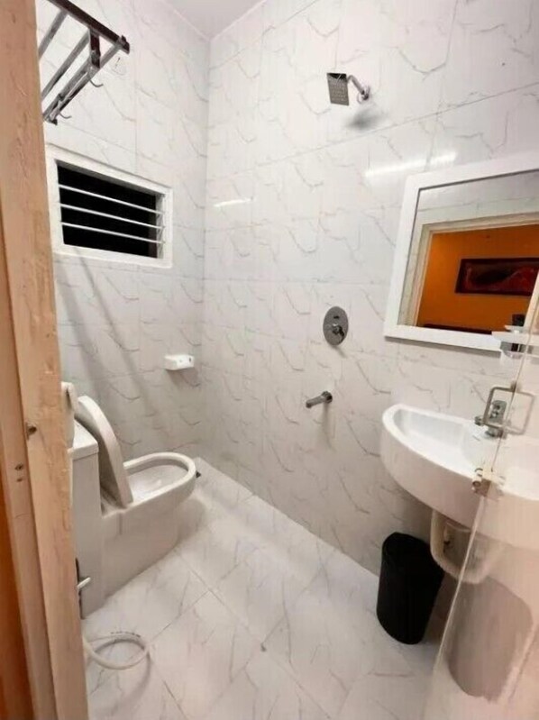 A bathroom with a toilet, bidet, sink, and a showerhead.
