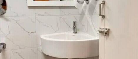 A bathroom with a white sink, a mirror, and a black trash bin.