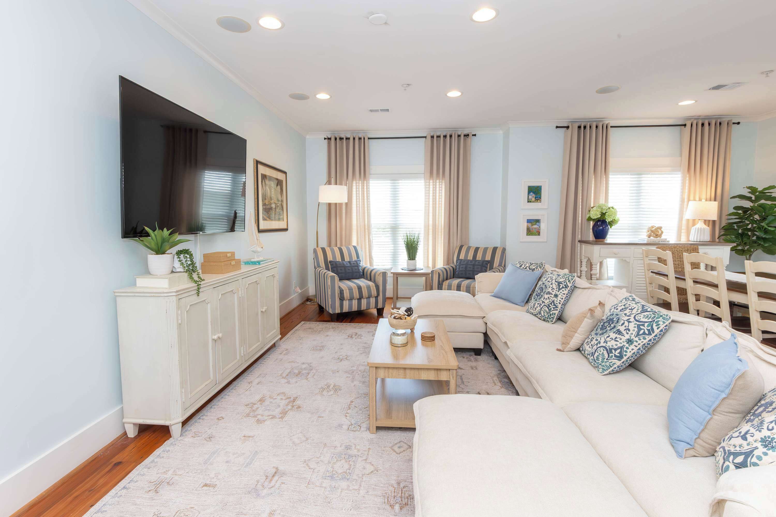 Een woonkamer met een bank, fauteuils, een salontafel, een televisie en een kast.