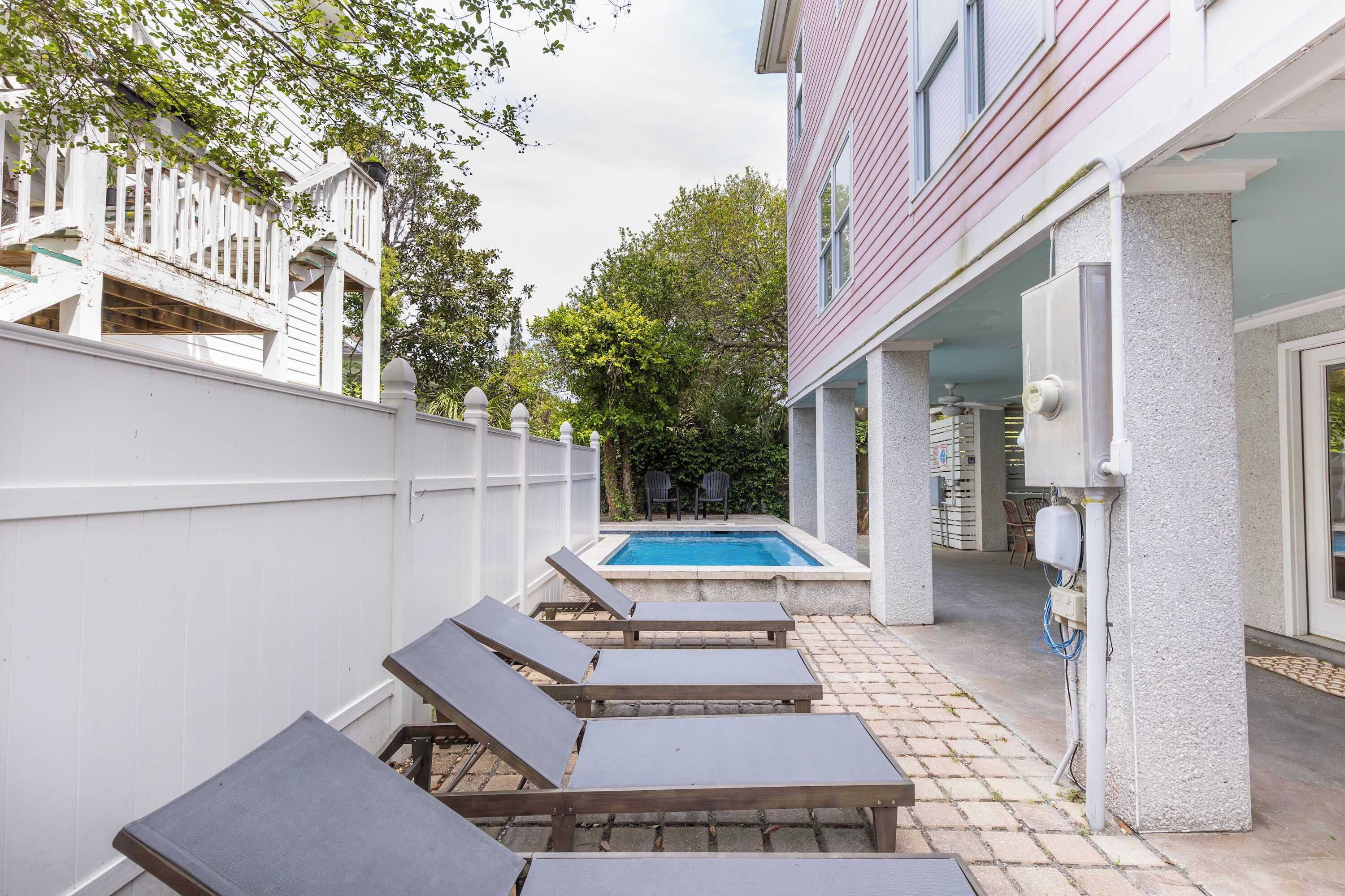 Un jardin avec une piscine, des chaises longues et un patio couvert.