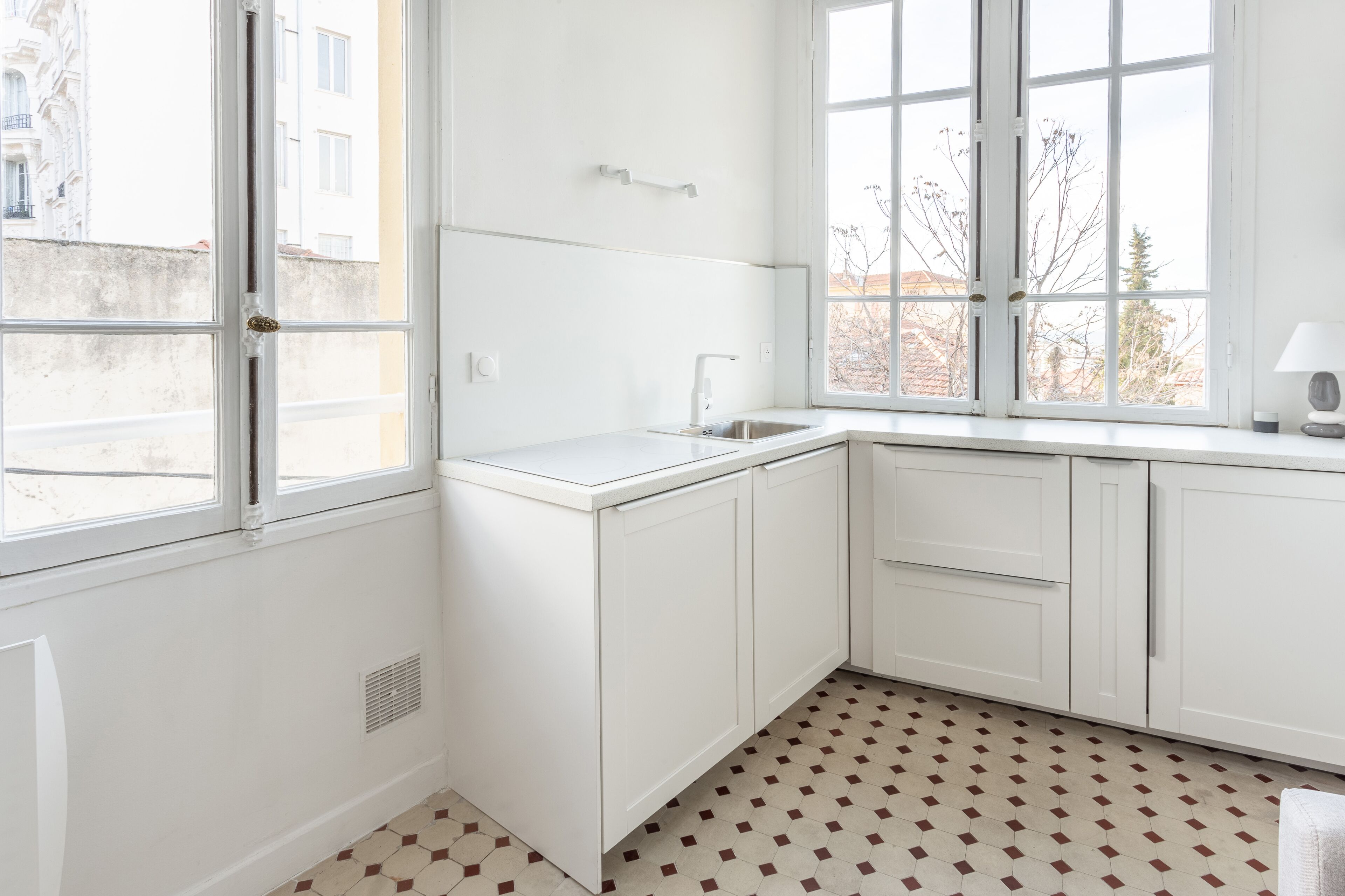 A kitchen with white cabinets, a sink, and a window with a view of buildings outside.