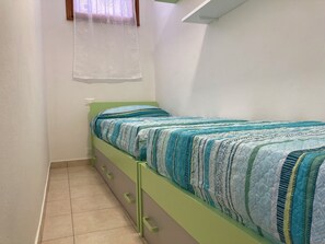 A small, single-bed room with a green bed frame, a window with a sheer curtain, and a plain white wall. - Lovely Flat in the Center of Rosolina Mare (Rosolina)