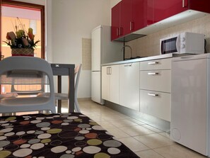 Una cocina moderna con armarios blancos, un microondas y un refrigerador.