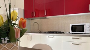 Une cuisine moderne avec des meubles rouges, un plan de travail blanc, un four à micro-ondes et un évier.