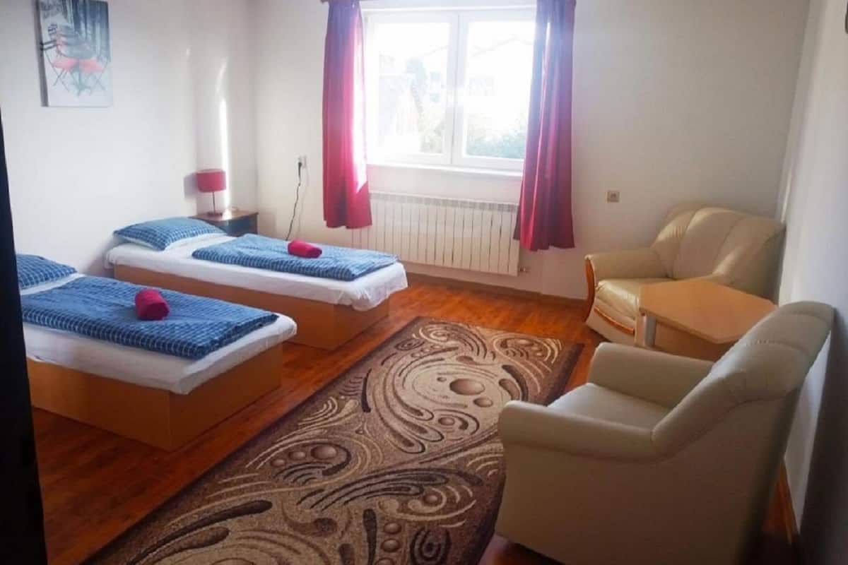 A room with two beds, a sofa, and a chair.