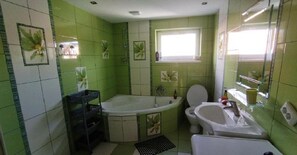 A bathroom with green tiles, a bathtub, a toilet, and a sink. - Lucky Cat  (Nova Lesna)
