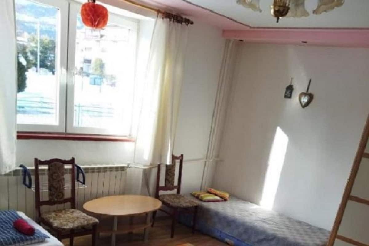 A small, cozy room with two beds, a table, and chairs.