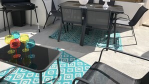 An outdoor patio with a table, chairs, a grill, and colorful glassware. - Maisont3 Duplex Avec Cour Privée à 400 Plage (Angoulins)