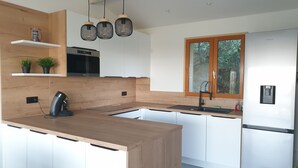 Een moderne keuken met een houten kookeiland, witte kasten, een ingebouwde oven en een raam met uitzicht op groen.