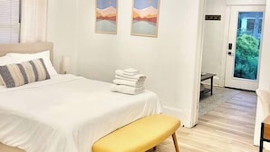 Ein Schlafzimmer mit Bett, Sitzbank, Deckenventilator und zwei Wandbildern.