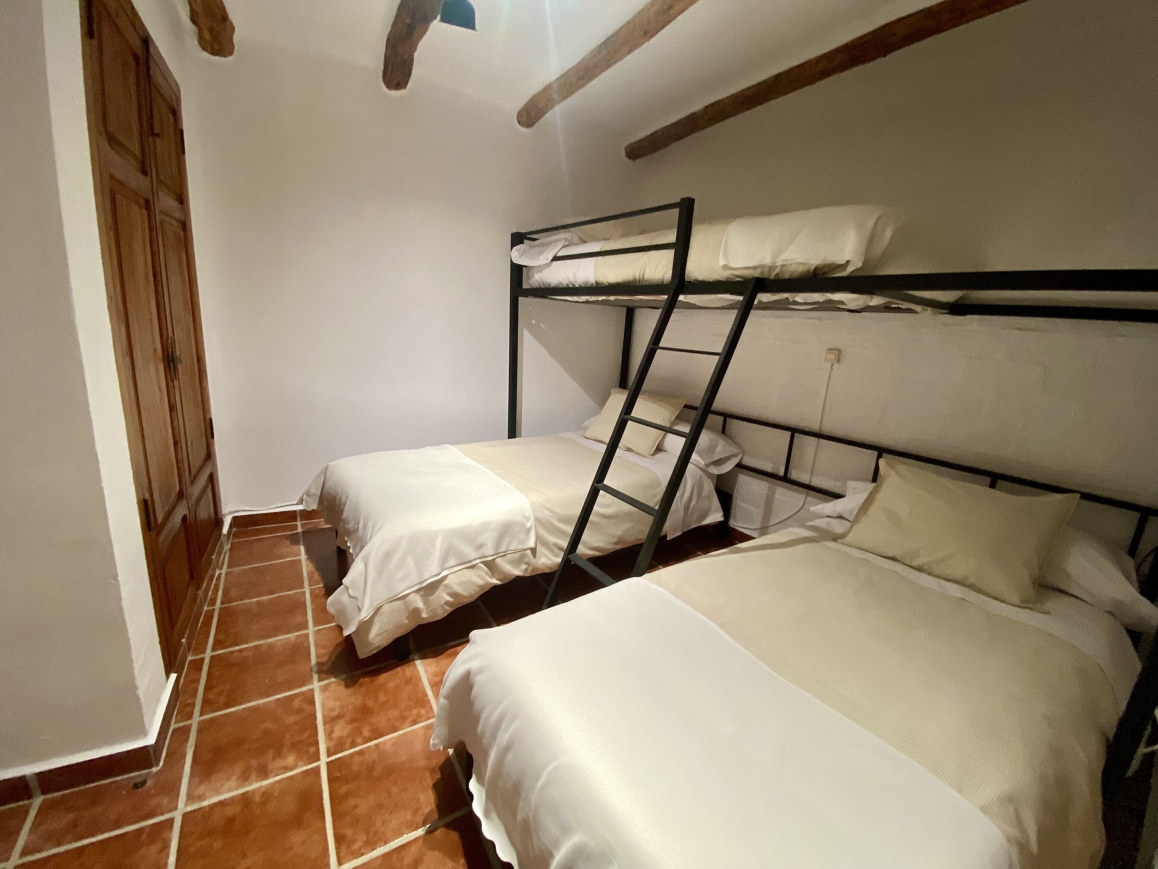 Un dormitorio con dos literas, un armario de madera y suelo de baldosas.