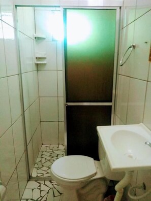 Une petite salle de bain comprenant des toilettes, un lavabo et une cabine de douche.