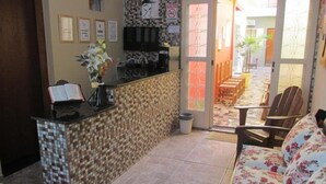 Un área de recepción con mostrador de baldosas, un sofá y un comedor con sillas y una mesa.