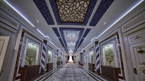 A grand hallway with a patterned carpet, ornate ceiling, and symmetrical doorways. - COMFORT HOTEL SAMARKAND (Samarkand)