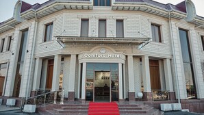 A large, historic building with a prominent arched entrance and a red carpet leading to the doors. - COMFORT HOTEL SAMARKAND (Samarkand)