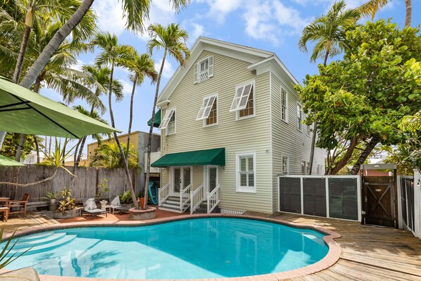 A two-story house with a swimming pool, surrounded by palm trees and a wooden deck. - Luxurious Island Pearl-Private Pool - 2BD/2Bath (Key West)