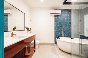 A modern bathroom with a white sink, a wooden vanity, a white toilet, and a glass-enclosed shower area.