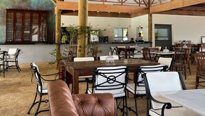 Un comedor interior con techo alto de madera, mesas, sillas y un gran mural en la pared.