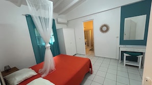 Un dormitorio con cama, mesita de noche, espejo y puerta que da a un baño.