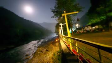 Vista nocturna de un río con un puente y una barandilla.